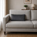 Plain rectangular charcoal grey filled cushion on a pale sofa.