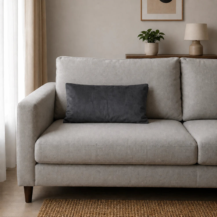 Plain rectangular charcoal grey filled cushion on a pale sofa.