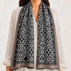 A black and white patterned scarf with Louis Vuitton monogram motifs, draped over the shoulders of a model wearing a white blouse.