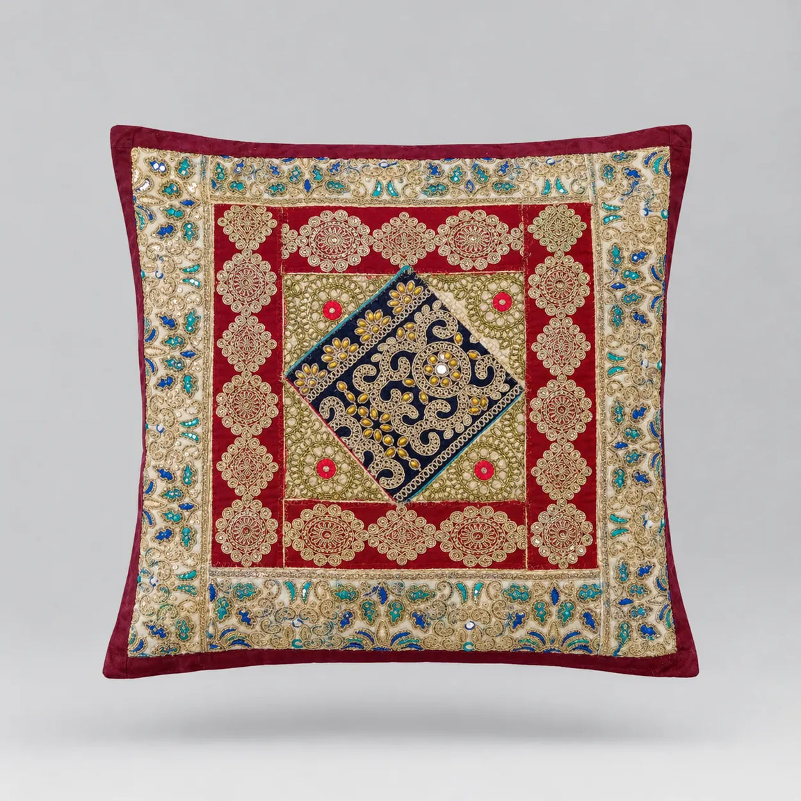 Burgundy-bordered cushion cover with red, cream and navy ornamental panels and a central diamond.