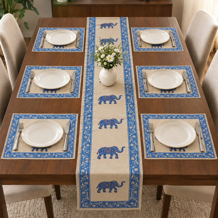 Alt Text: Wooden dining table set with white plates and cutlery, featuring a cream-colored table runner decorated with a repeating pattern of blue ornamental elephants and a blue floral border. with 6 mats