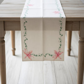 White table runner with delicate green borders and pink floral accents.