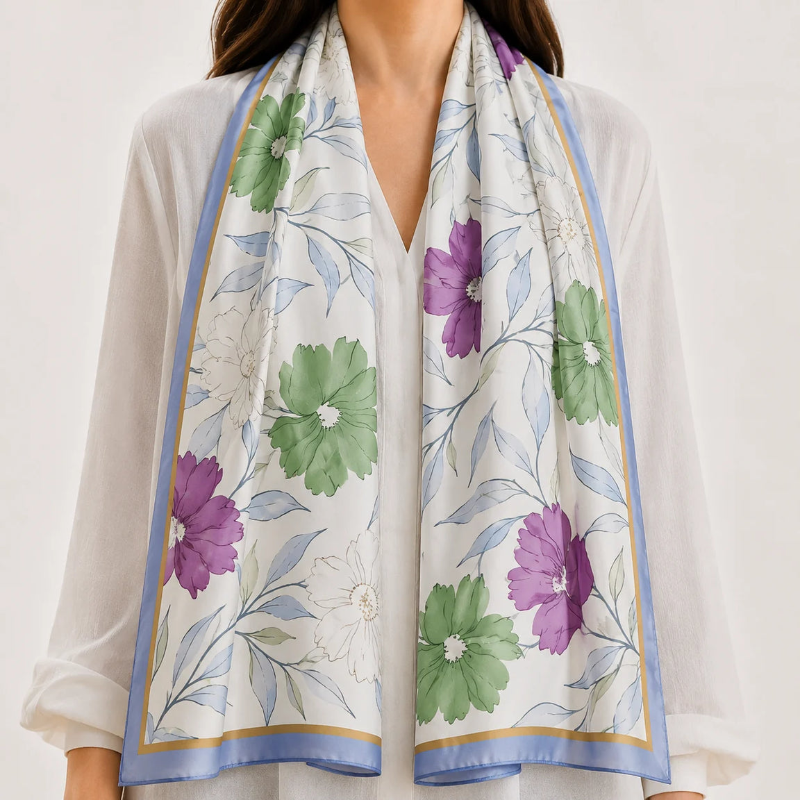 White scarf with purple flowers and green leaves draped over a white blouse.