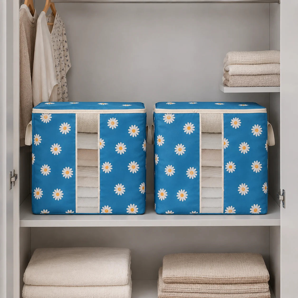 Two blue fabric storage bins with a white daisy pattern, filled with folded beige towels, displayed inside an open white closet on a shelf.