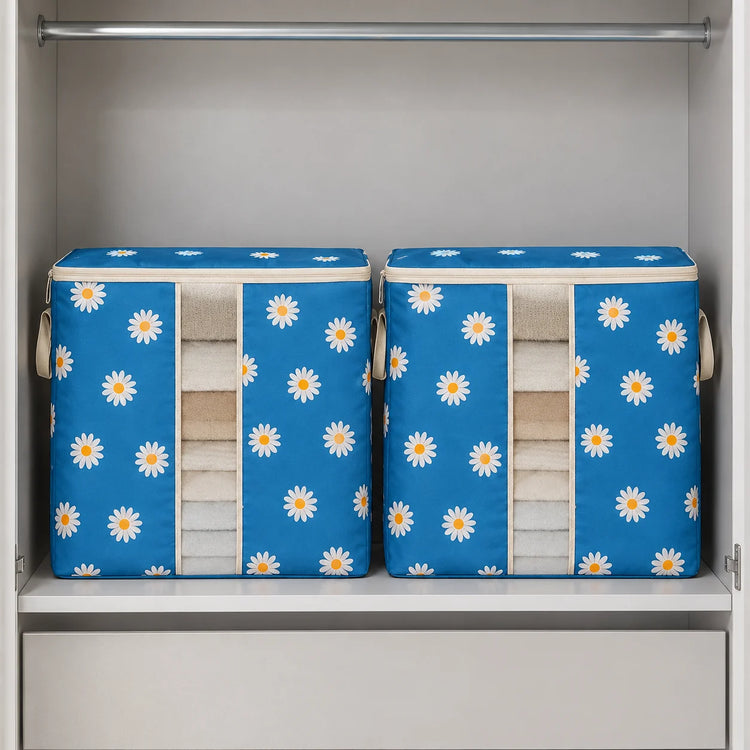 Two blue fabric storage bins with a white daisy pattern, neatly folded towels, displayed inside a white closet on a shelf.