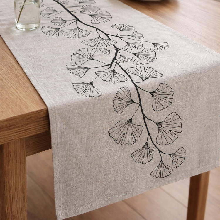 Light grey table runner with delicate black outlined leaves.