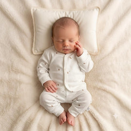Infant wearing a white outfit with front fastenings and small animal motifs
