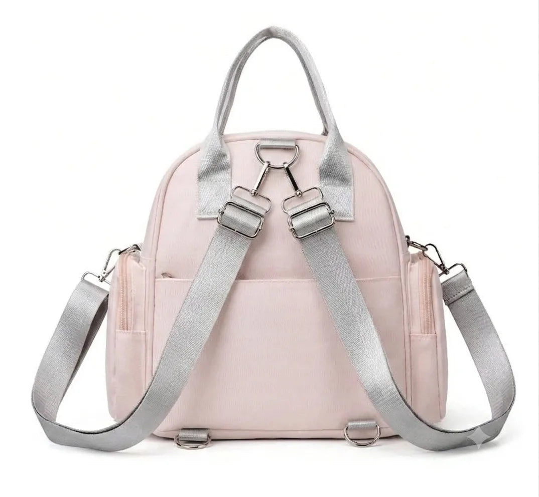 Rear view of a pale pink bag with gray adjustable backpack straps and carry handle