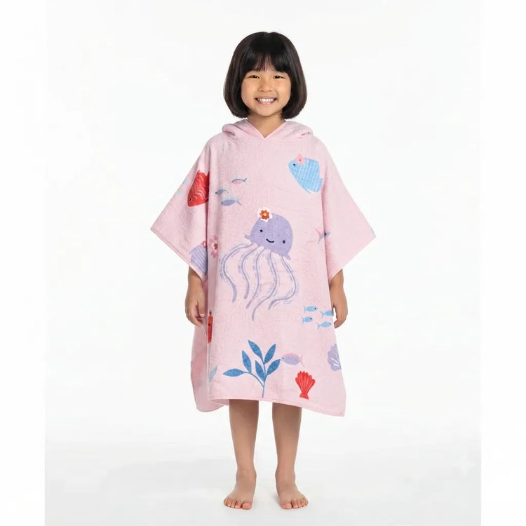 Child wearing a pink towel poncho with sea-life illustrations.