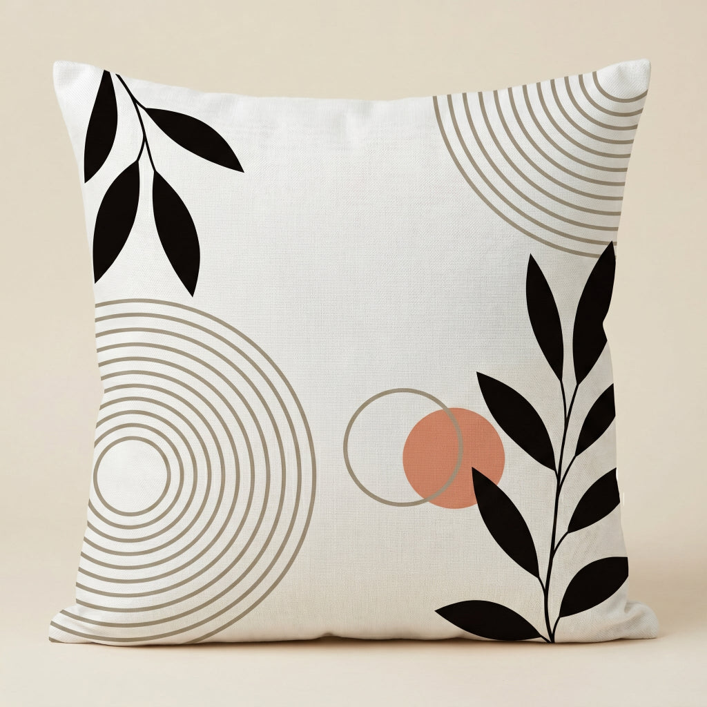 Cream cushion cover with black leaves, concentric circles and a small terracotta accent.