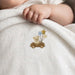Close-up of an infant's hand on a white blanket with a teddy bear in a car and balloons