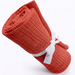 Rolled red cellular blanket tied with a white ribbon.