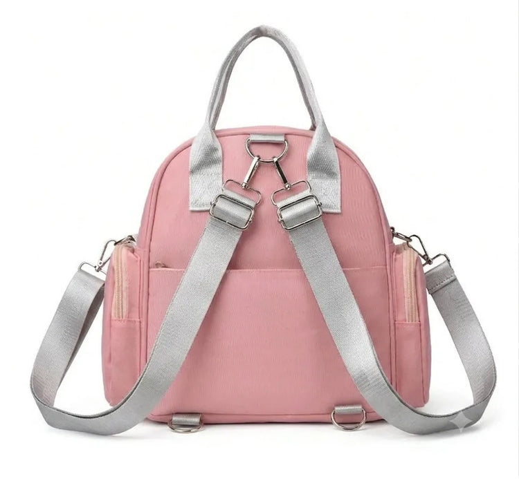 Rear view of a pink bag with gray adjustable backpack straps and carry handle