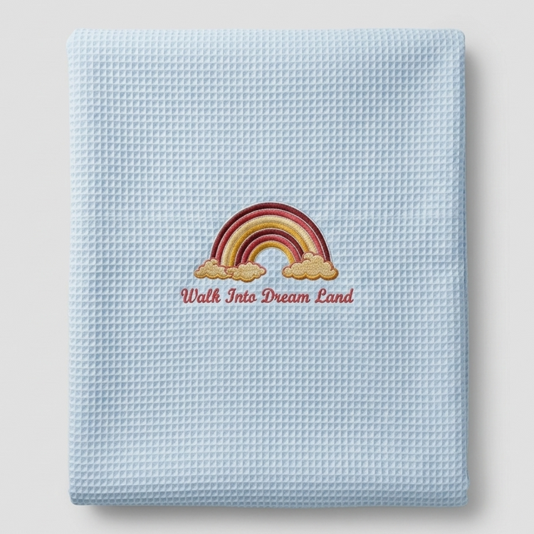Folded light blue waffle-weave baby blanket with a rainbow motif.