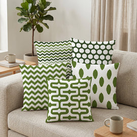 Five green and white cushion covers with zigzag, dot, leaf and geometric patterns.