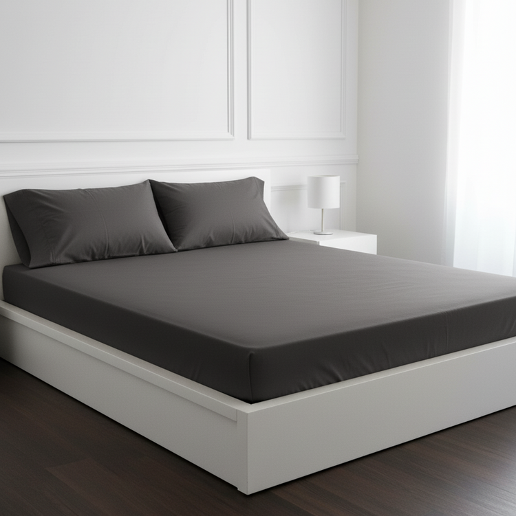 Charcoal grey fitted sheet and matching pillowcases on a white double bed.