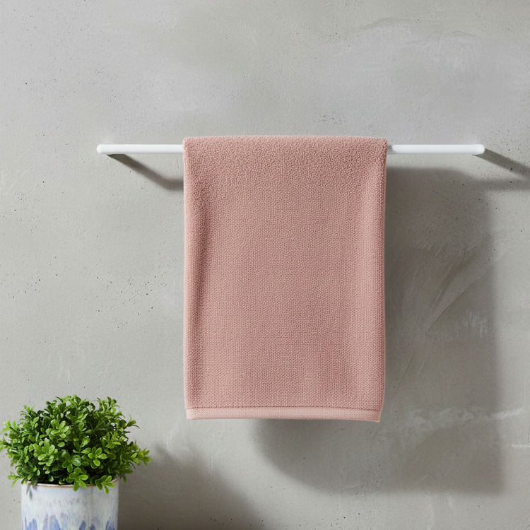 Tea pink bath towel draped over a bathroom towel rail.