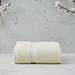One folded cream plain towel with a woven border.