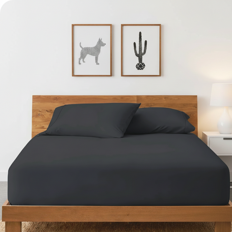 Black cotton fitted sheet displayed on a double bed with matching pillowcases.