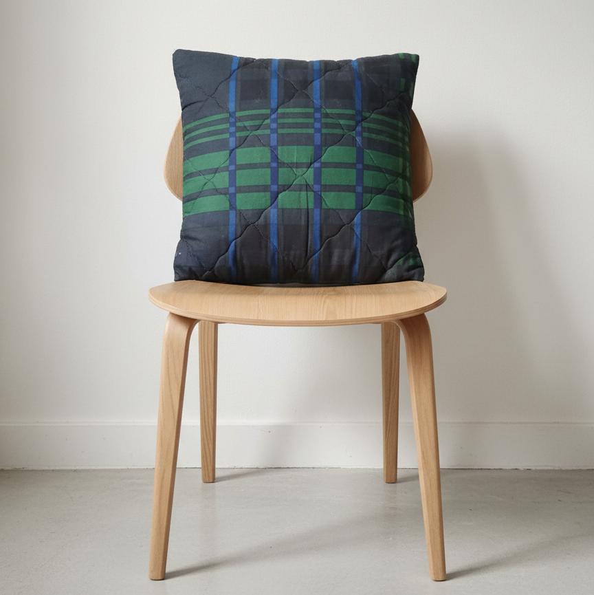 Navy and green plaid cushion displayed on a wooden chair.