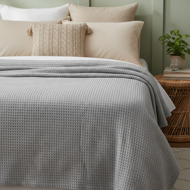 Light grey textured thermal blanket draped over a bed.