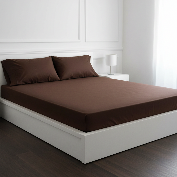 Chocolate brown fitted sheet and matching pillowcases on a white double bed.