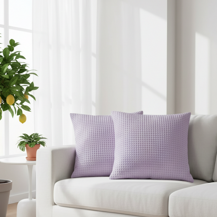 Two light purple cushion covers with a waffle texture displayed on a sofa.