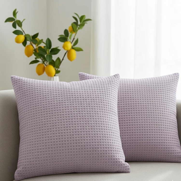 Two light purple cushion covers with a waffle texture displayed on a sofa.