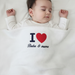 Infant under a white waffle-textured blanket with a red heart and Baba & mama lettering