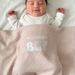 Beige waffle-textured baby blanket with white 'mamas BOY' lettering, shown covering a baby.