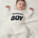 Infant under a white waffle-textured blanket with black mamas BOY lettering
