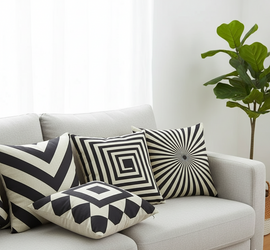 Black and cream geometric cushion covers arranged on a light grey sofa.