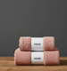 Tea pink face and hand towels stacked with labelled paper bands.