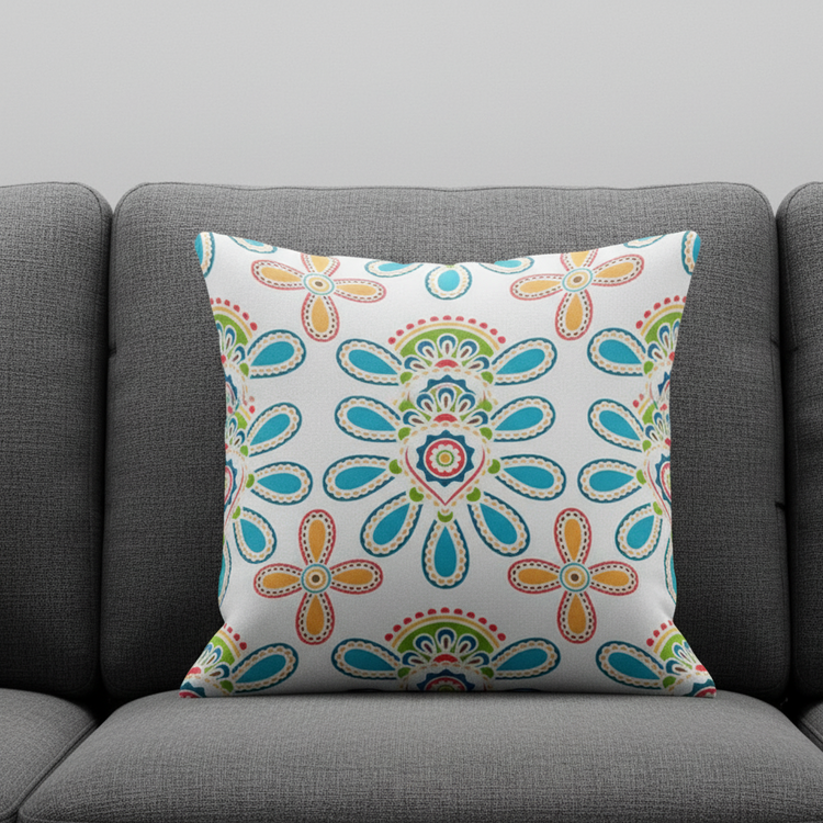 Cream cushion cover with colourful outlined flowers and decorative leaf shapes on a grey sofa.