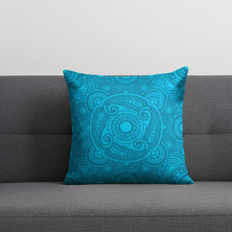 Turquoise cushion cover with a subtle intricate circular medallion on a grey sofa.