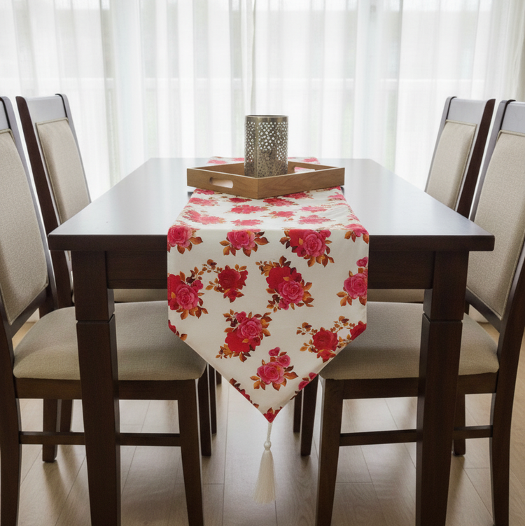 Cream table runner with red and pink roses on a dark dining table.