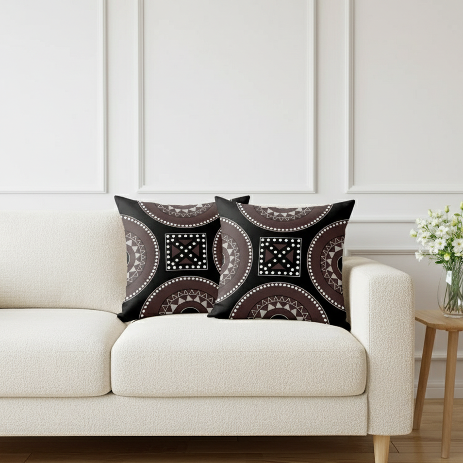 Two dark patterned cushion covers with circular and geometric motifs on a sofa.