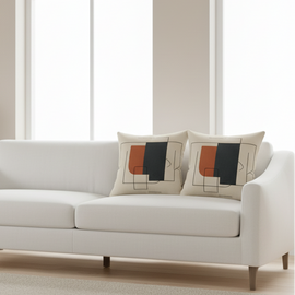 Two neutral cushion covers with small rust and black panels arranged on a cream sofa.