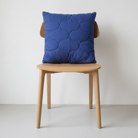 Blue cushion with a subtle overlapping circular pattern displayed on a wooden chair.