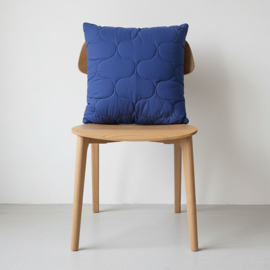 Blue cushion with a subtle overlapping circular pattern displayed on a wooden chair.