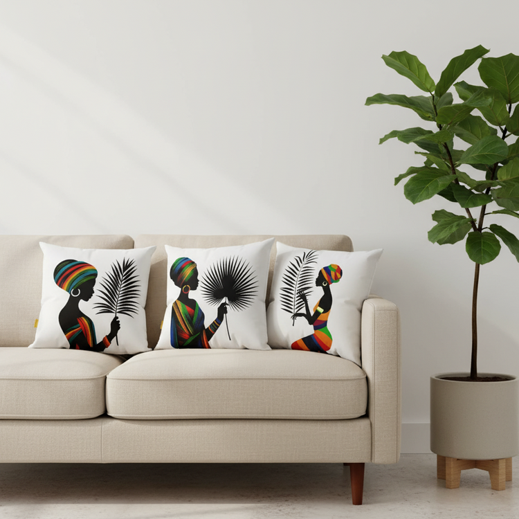 Three white cushion covers with colourful portraits and black leaves on a cream sofa.
