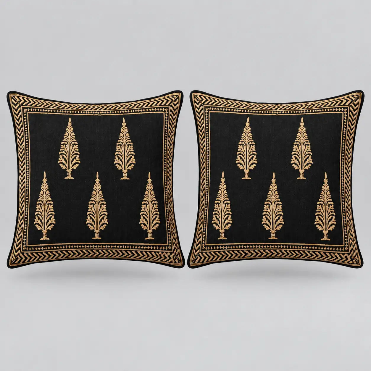 Two square black throw pillows with gold embroidered tree motifs and a decorative gold border, shown side by side on a light gray background.