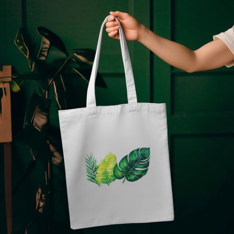 Cream tote bag with green leaves in contrasting shapes.