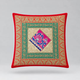 Red-bordered cushion cover with green ornamental borders and a pink and blue central diamond.