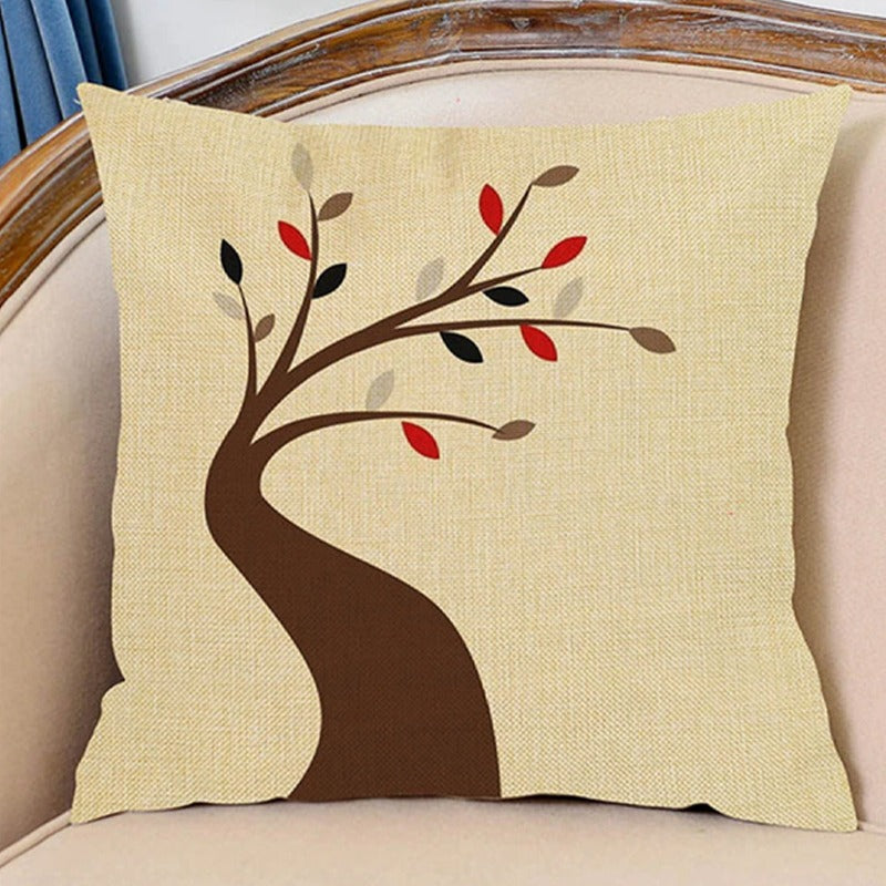 Cream cushion cover with a curved brown tree and sparse red and brown leaves.