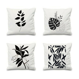 Four white cushion covers with black botanical prints.