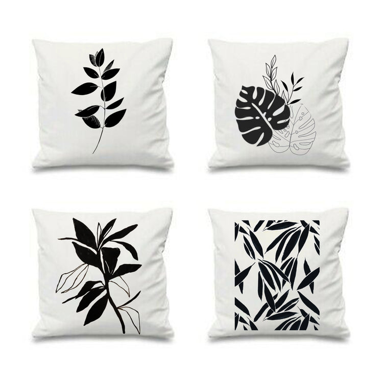 Four white cushion covers with black botanical prints.