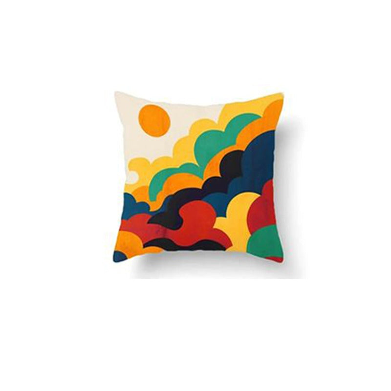 Cushion cover with layered yellow, orange, green and dark blue cloud shapes.