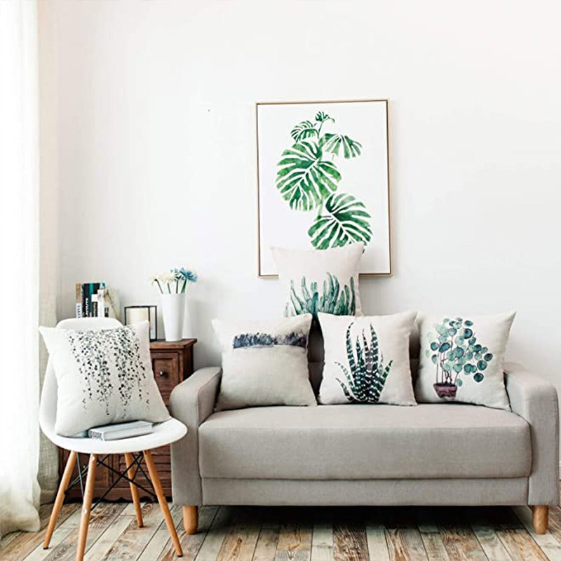 Botanical cushion covers arranged on a grey sofa in a bright living room.