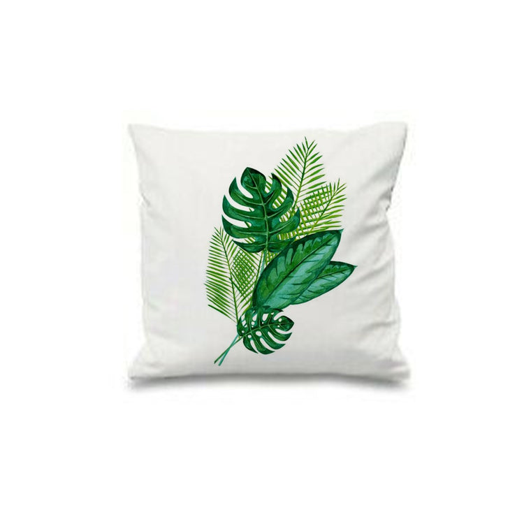 White cushion cover with overlapping green tropical leaves and pale geometric outlines.
